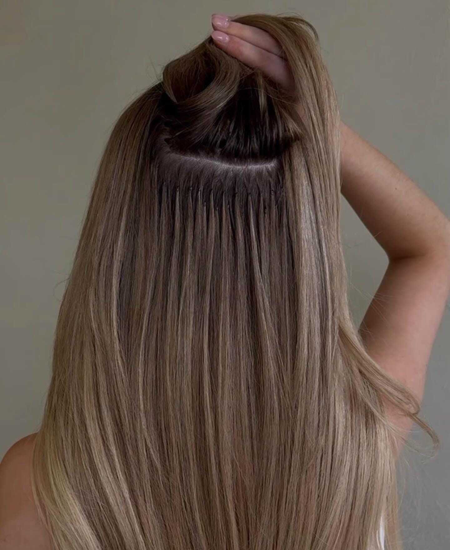 Hair extensions being applied to the back of a woman's head.